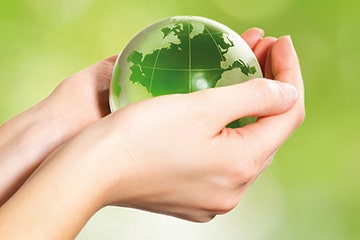 Hände halten grüne Glas-Erde